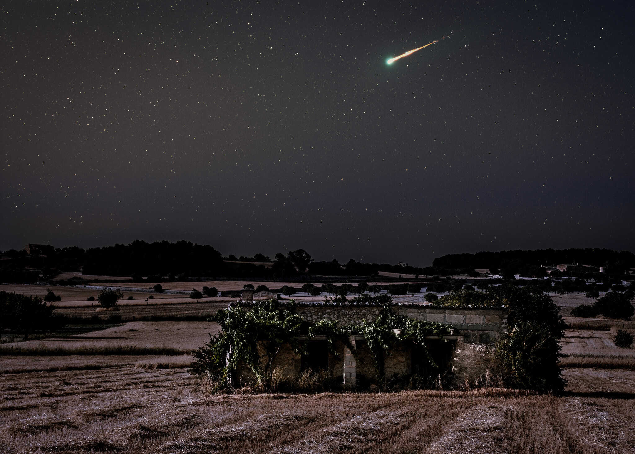 Astrocatástrofe con estrella fugaz sobre campo rural en la noche, fotografía nocturna de cielo estrellado, impresionante vista del firmamento, belleza natural y astronomía.