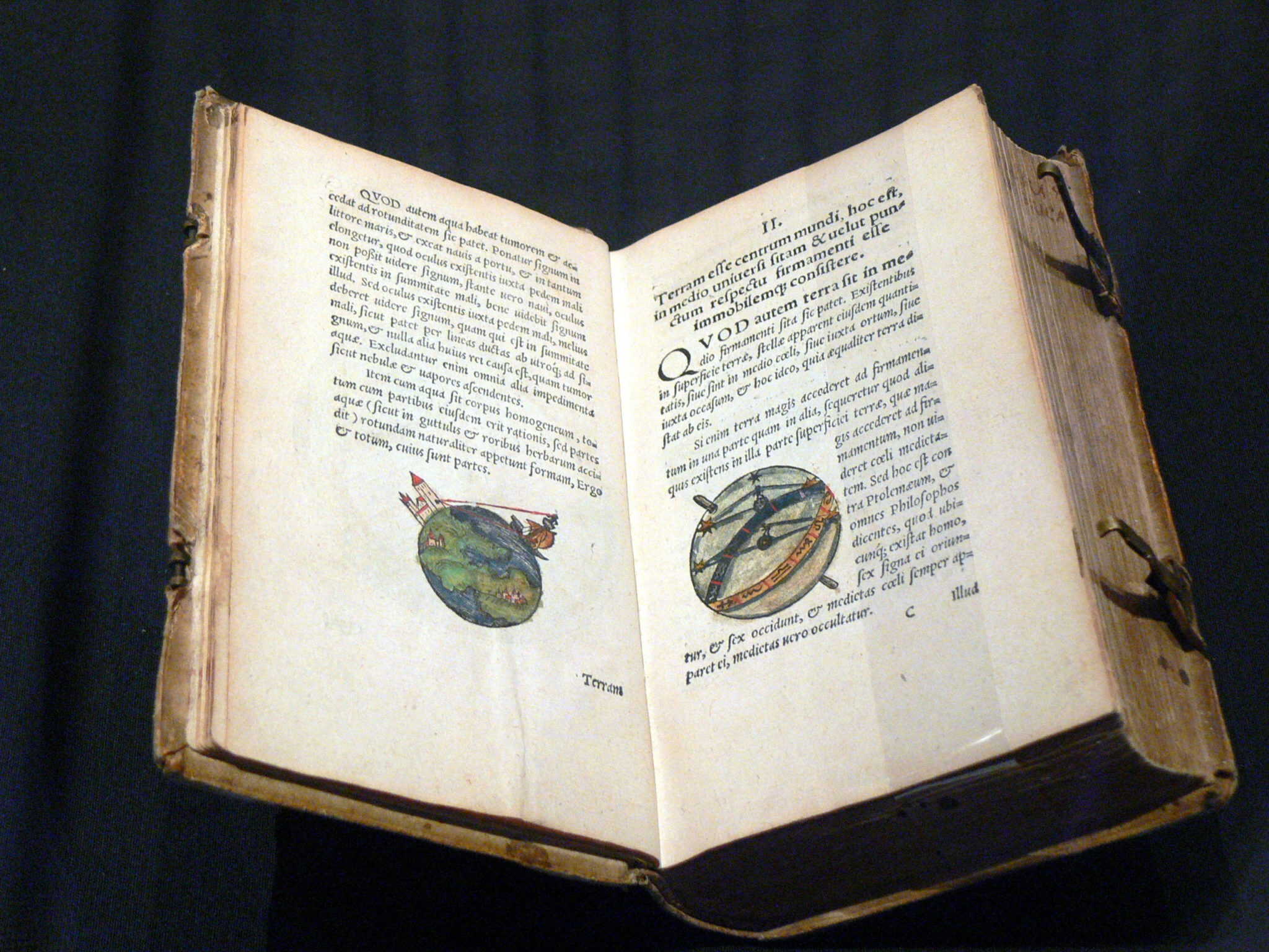 Antiguo libro de ilustraciones científicas y astronómicas con mapas y diagramas detallados, abierto en un texto en latín, en un fondo oscuro.